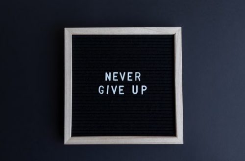 Inspirational letter board with 'Never Give Up' phrase on gray background.