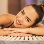 A happy woman with a bun relaxing and smiling at an indoor poolside, creating a warm and inviting atmosphere.